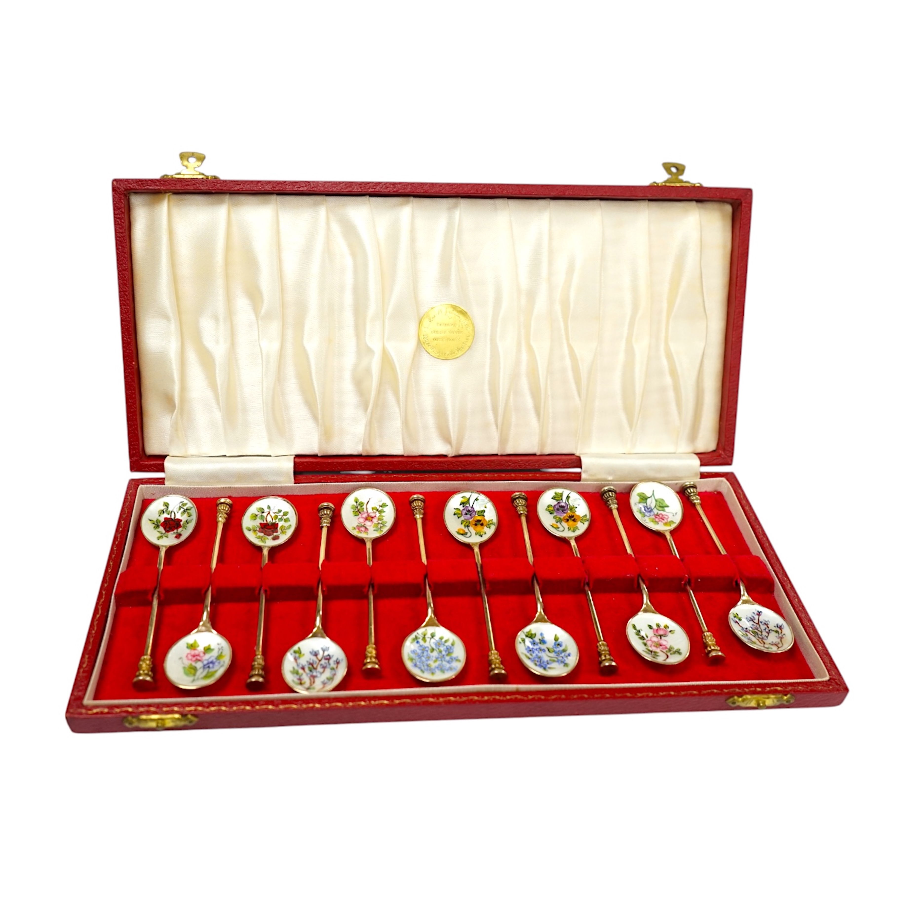 A cased set of twelve early 1970's silver gilt and enamel coffee spoons, decorated with flowers, S.J. Rose & Son, Birmingham, 1971, 98mm. Condition - fair to good